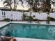 Backyard pool surrounded by tropical plants, a white fence, and a brick-style patio at 246 176Th E Ave, Redington Shores, FL 33708