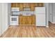 Efficient kitchen featuring wood cabinets, white appliances, and light wood flooring at 7450 35Th N St # 1604, Pinellas Park, FL 33781