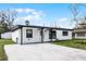 Modern white house with black accents, a carport, and a well-manicured lawn at 6615 Del Prado Ter, New Port Richey, FL 34652