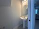 Small powder room with pedestal sink and round mirror at 5046 Avalon Park Blvd, Wesley Chapel, FL 33545
