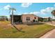 Single-story home with a green lawn, tall palm tree, and covered parking at 313 Mariner Dr, North Port, FL 34287