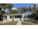 Charming single-story home with a light gray exterior and blue accent, surrounded by mature trees and a sidewalk leading to the front door at 5809 N 17Th St, Tampa, FL 33610