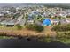 An aerial view of a large neighborhood with blue tarps on several roofs, showcasing the community layout and proximity to a body of water at 16605 Myrtle Sand Dr, Wimauma, FL 33598