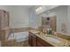 Well-lit bathroom featuring a bathtub, double sinks, a large mirror, and neutral tile at 16605 Myrtle Sand Dr, Wimauma, FL 33598