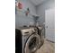 Modern laundry room with stainless steel appliances, tile flooring, and built-in shelving at 16605 Myrtle Sand Dr, Wimauma, FL 33598