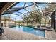 In-ground pool with screened enclosure and brick pool deck with lounge chairs and a small fountain at 16605 Myrtle Sand Dr, Wimauma, FL 33598