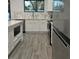 Well-lit kitchen showcasing gray wood-look flooring, modern appliances, and white cabinets at 302 E Clay Ave, Brandon, FL 33510