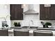 Kitchen island features stainless steel faucet, dark cabinets, white textured backsplash, and pendant lights at 5916 Jensen View Ave, Apollo Beach, FL 33572