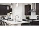 Modern kitchen island featuring stainless steel faucet, dark cabinets, and white textured backsplash at 5916 Jensen View Ave, Apollo Beach, FL 33572