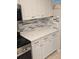 Kitchen boasts white cabinets, quartz counters, and tile backsplash at 721 Plumbrook Rd, Sun City Center, FL 33573