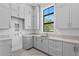 Bright laundry room with gray cabinets, quartz countertops, and a window at 5032 W Longfellow Ave, Tampa, FL 33629