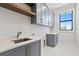 Laundry room with gray cabinets, quartz countertops, and a farmhouse sink at 5032 W Longfellow Ave, Tampa, FL 33629