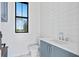 Modern powder room with white shiplap walls, marble floor, and blue vanity at 5032 W Longfellow Ave, Tampa, FL 33629