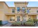 Two-story townhome with light-yellow exterior, landscaping, and walkway at 37658 Aaralyn Rd, Zephyrhills, FL 33542