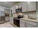 Modern kitchen with gray cabinets, stainless steel appliances, and granite countertops at 7516 Cypress Walk Dr, New Port Richey, FL 34655