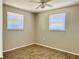 Bright bedroom with two windows, ceiling fan, and wood-look tile floor at 3615 Wellington Dr, Holiday, FL 34691