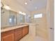 Bright bathroom featuring double vanities, a large mirror, and walk-in shower with glass door at 1817 Pacific Dunes Dr, Sun City Center, FL 33573