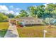 Tan house with landscaped yard, walkway, and American flag at 6921 Onyx N Dr, St Petersburg, FL 33702