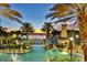 Lighted pool area at sunset with palm trees and a lighthouse at 5239 Admiral Pointe Dr, Apollo Beach, FL 33572