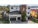 Aerial view of a modern two-story home with two-car garage, a black metal roof, and a lushly landscaped yard at 5006 W San Miguel St, Tampa, FL 33629