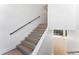 Modern staircase featuring wood treads, black handrail, and light-filled landing leading to the next level at 5006 W San Miguel St, Tampa, FL 33629