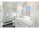 Modern bathroom with white vanity, light green tile shower, and herringbone floor at 3011 W Asbury Pl, Tampa, FL 33611