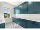 Bright laundry room featuring blue cabinets and a hexagon tile floor at 3011 W Asbury Pl, Tampa, FL 33611