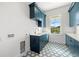 Modern laundry room with blue cabinets, hexagon tile floor, and window at 3011 W Asbury Pl, Tampa, FL 33611