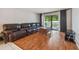 Spacious living room with dark leather sofa, wood floors, and sliding glass door to balcony at 3114 Lake Pine Way # H2, Tarpon Springs, FL 34688