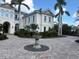 Cream-colored house with a circular driveway with fountain, lush greenery, and tall palm trees at 19451 Ganton Ave, Bradenton, FL 34202