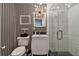 Stylish bathroom with black and white striped wallpaper and glass shower at 221 Howard Dr, Belleair Beach, FL 33786