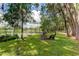 Serene lakeside backyard with fire pit, lounge chairs, and a dock at 17210 Orangewood Dr, Lutz, FL 33548