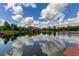 Stunning lake view with lush greenery and fluffy clouds reflecting on the water at 17210 Orangewood Dr, Lutz, FL 33548