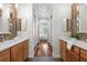 Hallway view of bathroom with dual vanities, mosaic-tiled walls, and neutral color scheme at 6030 Printery St # 105, Tampa, FL 33616