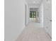 Long hallway with white walls and light wood-look tile flooring, leading to living area at 1877 Pepper Grass Dr, North Port, FL 34289