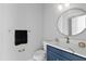 Elegant powder room features a navy blue vanity, a round mirror, and stylish gold fixtures at 2724 W Dewey St, Tampa, FL 33607