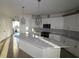 Modern kitchen with white cabinets, quartz countertops, and geometric light fixtures at 683 Allora Ave, Nokomis, FL 34275