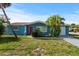 Charming light blue single story home with red door, landscaping, and driveway at 3022 Holiday Lake Dr, Holiday, FL 34691