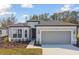 Single-story home with gray siding, two-car garage, and landscaping at 1279 Kazaz Ct, Zephyrhills, FL 33540