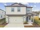 Two-story house with gray and white siding, a two-car garage, and a landscaped yard at 1209 Kistna Dr, Zephyrhills, FL 33540