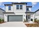 Two-story house with gray garage door and landscaping at 1201 Kistna Dr, Zephyrhills, FL 33540