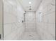 Large walk-in shower with marble-style tile and small window for ventilation at 8320 Boxwood Dr, Tampa, FL 33615