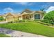 Tan three-car garage home with lush landscaping and a large front yard at 806 Red Ash Ct, Seffner, FL 33584