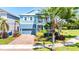 Two-story light blue house with a brick driveway, landscaping, and palm trees at 905 Seagrape Dr, Ruskin, FL 33570