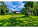 Spacious backyard with lush grass and mature trees surrounding a charming house at 4502 Hill Dr, Valrico, FL 33596