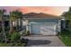 Charming home exterior with a paved driveway, well-manicured lawn, and lush tropical landscaping at 4838 Sevilla Shores Dr, Wimauma, FL 33598