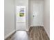 Hallway with light wood-style flooring and an open door to carpeted room with a view to the neighborhood at 10288 Surrey Rose Dr, San Antonio, FL 33576