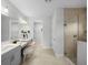 Stylish main bathroom featuring dual sinks, tiled walk-in shower, and a dressing table at 9120 Warm Springs Cir, Parrish, FL 34219
