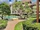 Community pool with a walkway and tropical landscaping at 3035 Countryside Blvd # 14B, Clearwater, FL 33761