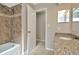 Bathroom showing decorative tile in the tub and shower, and a white door leading to a hallway at 10113 Tarragon Dr, Riverview, FL 33569